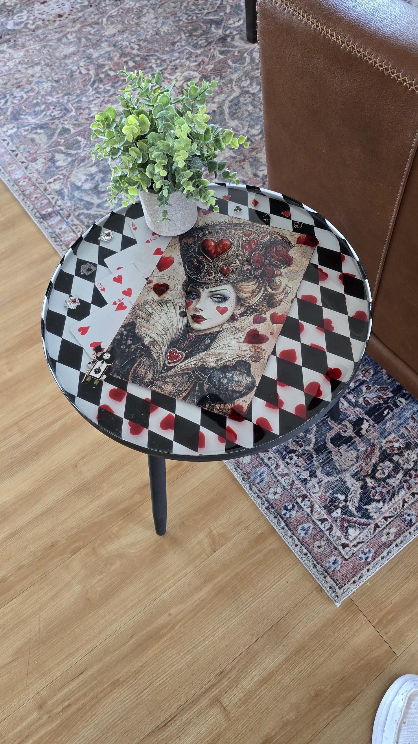 Round Queen of Hearts inspired end table with black and white checker background, preserved in crystal clear resin.