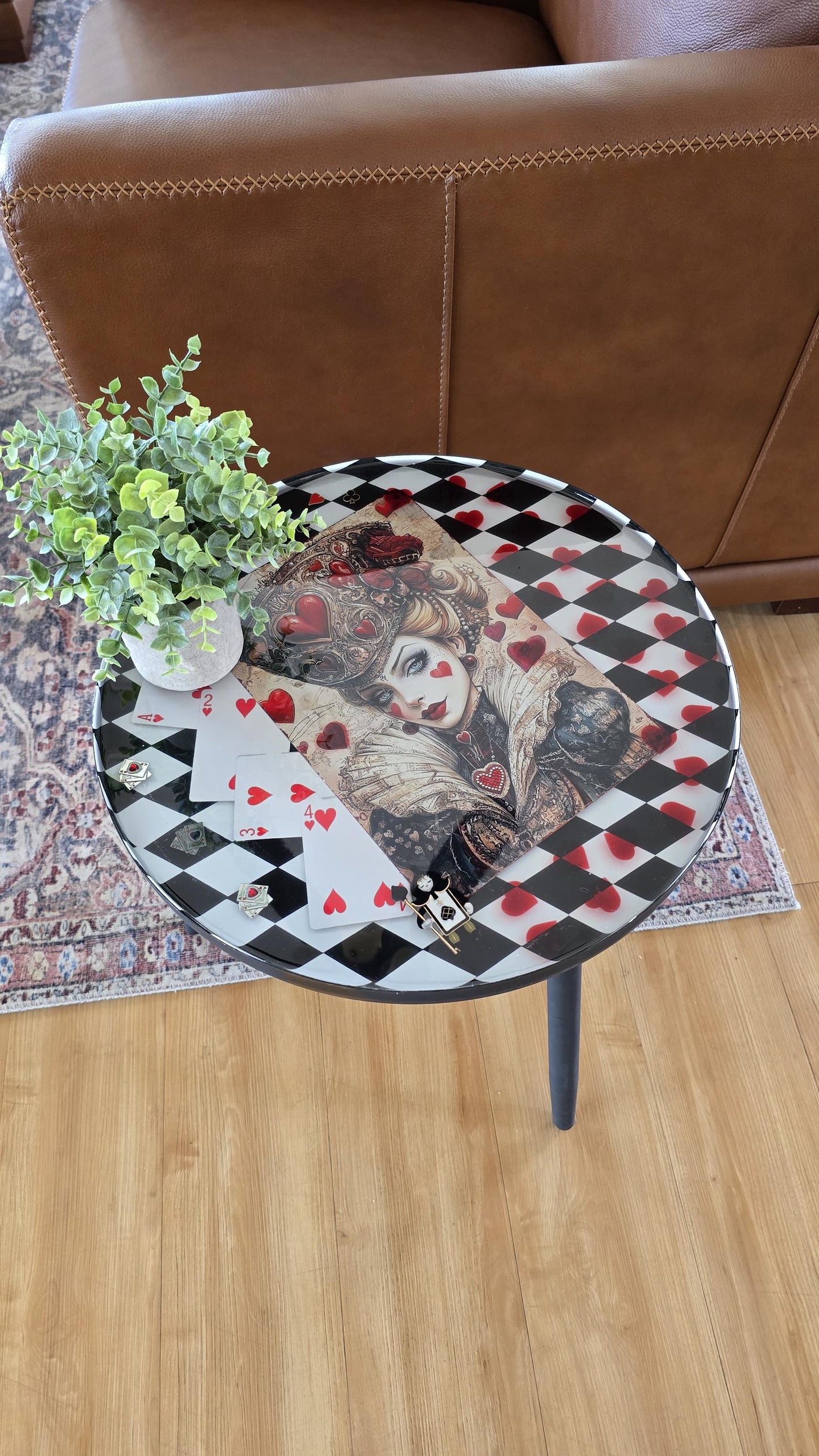 Round Queen of Hearts inspired end table with black and white checker background, preserved in crystal clear resin.